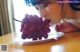 A woman is eating a bunch of grapes on a plate.