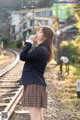 A woman in a school uniform standing on a train track.