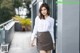 A woman in a white shirt and brown skirt posing for a picture.