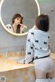 A woman brushing her teeth in front of a mirror.