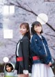 A couple of women standing next to each other in front of a tree.