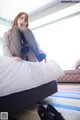 A woman sitting on top of a bed with her legs crossed.