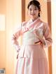 A woman in a pink and white hanbok poses for a picture.