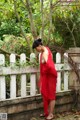 A woman in a red dress standing next to a white fence.