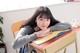 A young woman sitting at a desk with a book.