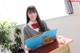 A young woman sitting at a desk holding a book.