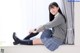 A young woman sitting on a window sill wearing a school uniform.