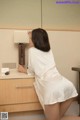 A woman in a white robe is sitting on a desk.