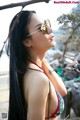 A woman in a bikini and sunglasses on the beach.