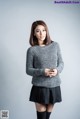 A woman in a gray sweater and black skirt posing for a picture.