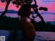 A naked woman sitting in a pool of water at sunset.