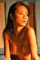 A naked asian woman sitting on a wooden bench.