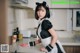 A woman in a maid outfit standing in a kitchen.