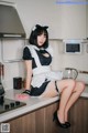 A woman in a maid outfit sitting on a kitchen counter.