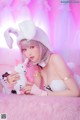 A woman in a bunny costume holding a stuffed animal.