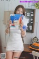 A woman in a white dress holding up a magazine.