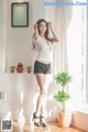 A woman standing in front of a window next to a plant.