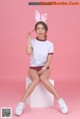 A woman sitting on top of a white cube wearing bunny ears.