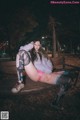 A woman sitting on a bench in a park at night.