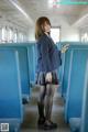 A woman in a school uniform standing on a train.