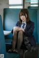 A woman in a school uniform sitting on a blue chair.