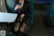 A woman in a school uniform is sitting on a train.