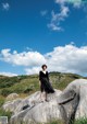 A woman standing on top of a large rock.