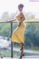 A woman in a yellow dress standing on a balcony.