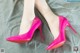 A pair of pink high heels on a gray background.