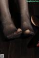 A close up of a woman's feet in black stockings and high heels.