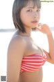 A woman in a red and white striped bikini on the beach.