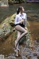 A woman sitting on a rock in the water.