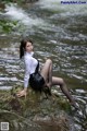 A woman sitting on a rock in the water.