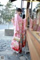 A woman in a pink kimono standing in front of a store.