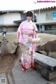 A woman in a kimono standing next to a herd of deer.