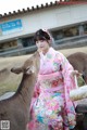 A woman in a pink kimono feeding a deer.