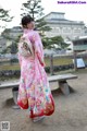 A woman in a pink kimono standing in front of a building.