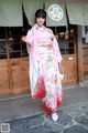 A woman in a pink kimono standing in front of a building.