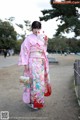 A woman in a pink kimono holding a white cat.