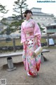 A woman in a pink kimono standing in front of a building.