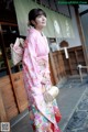 A woman in a pink kimono standing in front of a building.