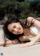 A woman laying on the sand in a white bikini.