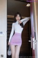 a woman in a white top and pink skirt posing for the camera