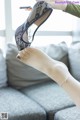 A woman is putting on a pair of black lace shoes.