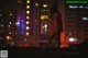 A naked woman standing on top of a building at night.