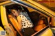 A woman sitting in the back seat of a yellow car.