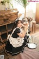 A woman in a black and white maid outfit holding a broom.