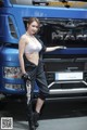 A woman standing in front of a blue truck.