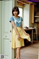 A woman standing in front of a door wearing a yellow skirt.