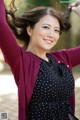 A woman in a polka dot dress and a maroon cardigan.